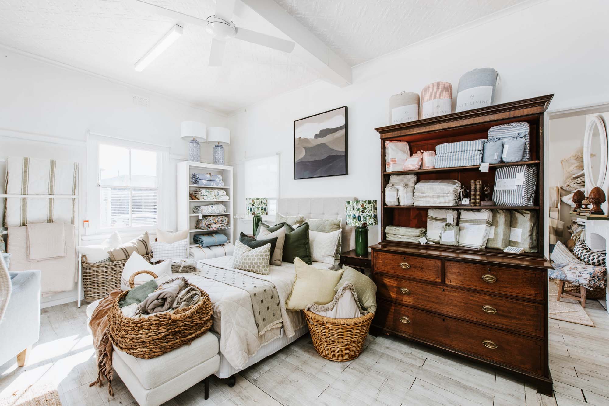 The interior of the Cloth & Feather store with a bed, dresser, and wicker baskets.