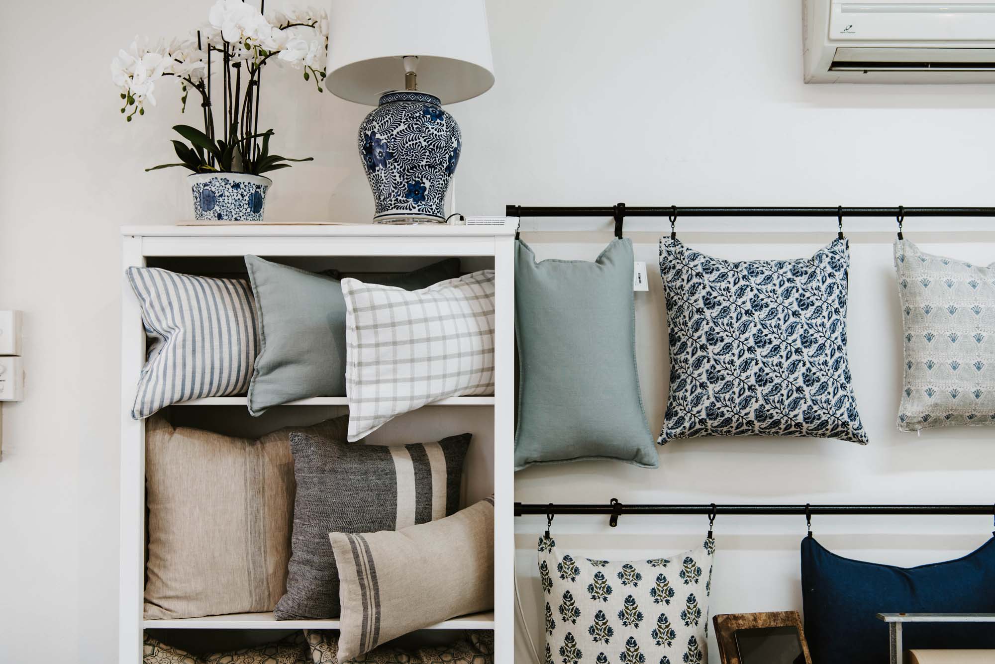 A display of blue and white pillows on a shelf.