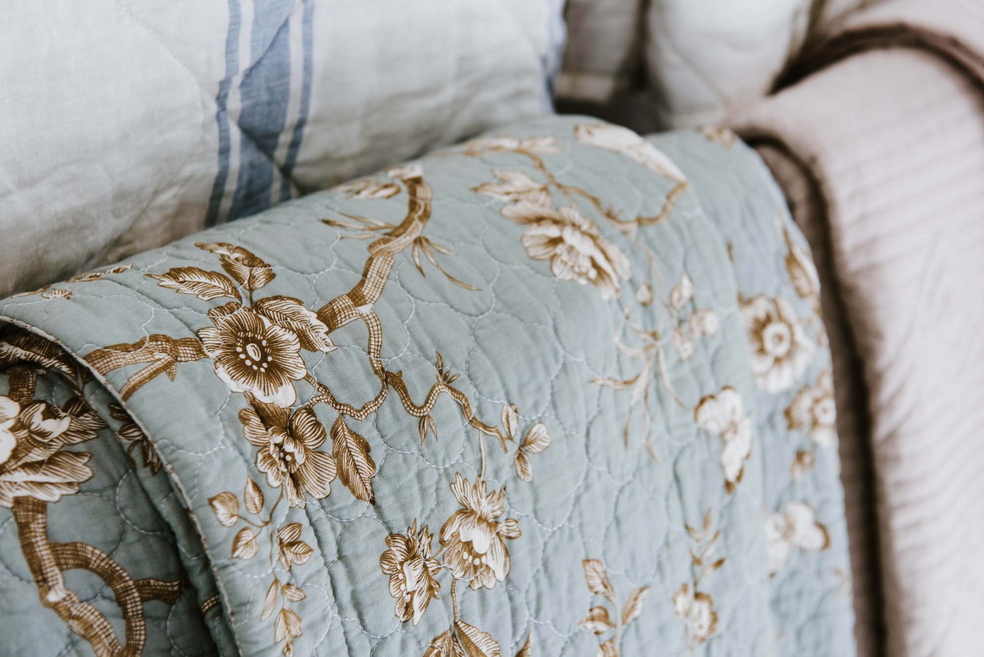 A bed with blue and white quilts and pillows.