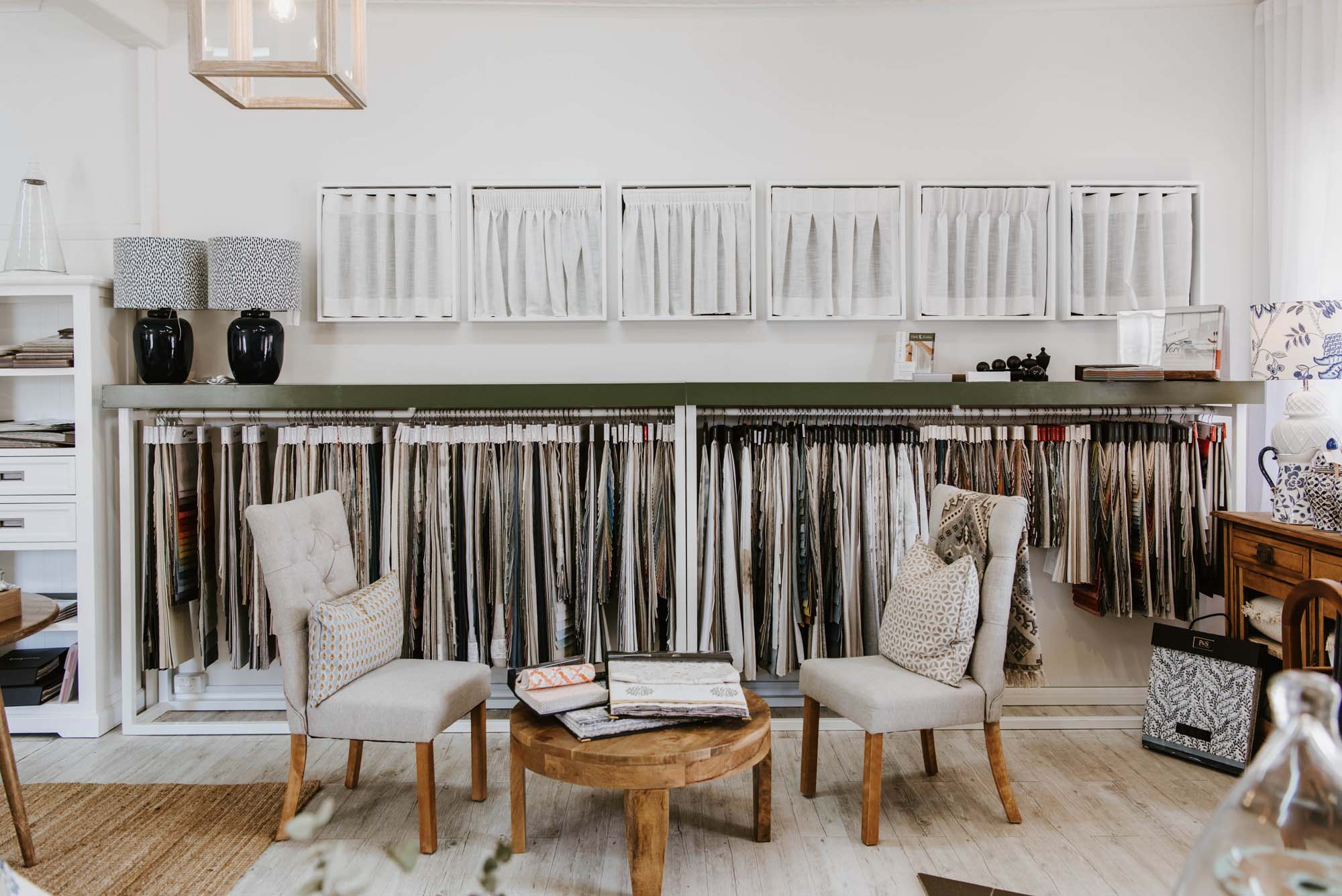 The interior of the Cloth & Feather store filled with furniture and a rack of rugs and fabrics.