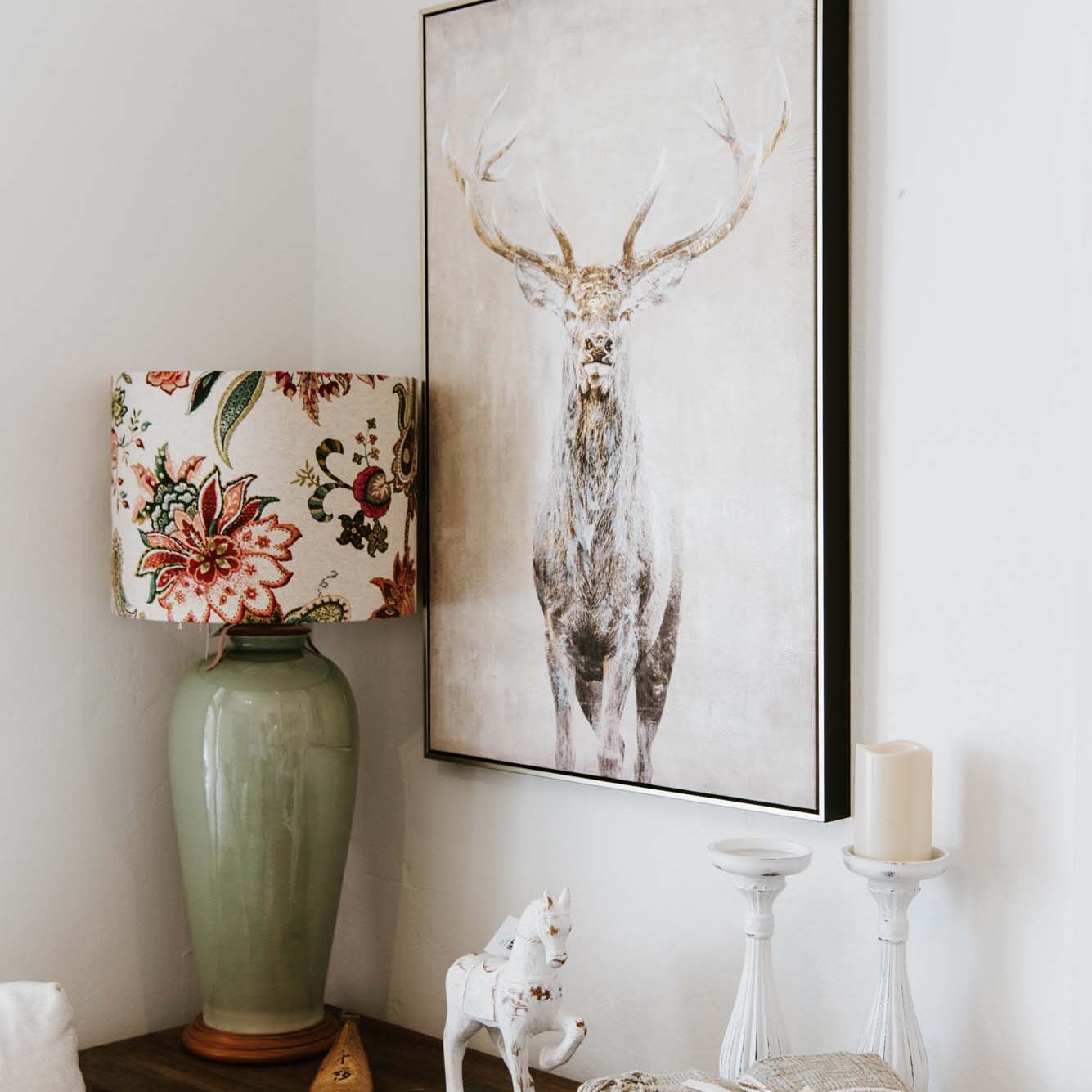 A living room with a deer painting on the wall.