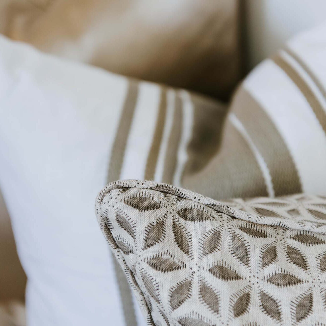 A close up of a beige and white pillow.